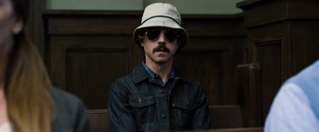 Movie still from “Ted 2” (2015), directed by Seth MacFarlane – A man wearing a hat and sunglasses sitting in a courtroom; Close Up shot, Low angle