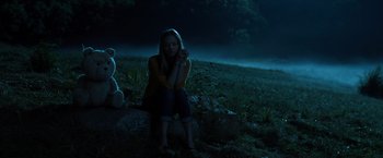 Movie still from “Ted 2” (2015), directed by Seth MacFarlane – A woman sitting on a rock next to a teddy bear; Medium shot, Low angle