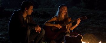 Movie still from “Ted 2” (2015), directed by Seth MacFarlane – A group of young people sitting around a campfire playing guitar; Medium shot, Over the shoulder angle