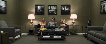 Movie still from “Ted 2” (2015), directed by Seth MacFarlane – A man and a woman sitting on a couch next to a teddy bear; Wide shot, Low angle