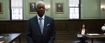 Movie still from “Ted 2” (2015), directed by Seth MacFarlane – An older man wearing a suit and tie in front of two paintings; Medium shot, Low angle