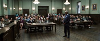 Movie still from “Ted 2” (2015), directed by Seth MacFarlane – A man standing in front of a group of people in a courtroom; Wide shot, High angle