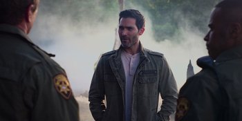 Movie still from “Teen Wolf: The Movie” (2023), directed by Russell Mulcahy – A man in a military jacket standing in front of a tree; Medium shot, Over the shoulder angle