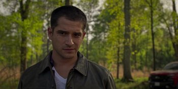 Movie still from “Teen Wolf: The Movie” (2023), directed by Russell Mulcahy – A person wearing a jacket near a forest; Close Up shot, Over the shoulder angle