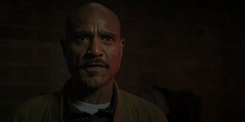 Movie still from “Teen Wolf: The Movie” (2023), directed by Russell Mulcahy – A bald man with a goatee stares into the camera; Close Up shot, Low angle