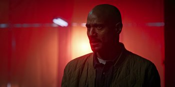 Movie still from “Teen Wolf: The Movie” (2023), directed by Russell Mulcahy – A bald man in a brown jacket is in the dark; Close Up shot, Low angle