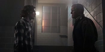 Movie still from “Teen Wolf: The Movie” (2023), directed by Russell Mulcahy – Two men standing next to each other in front of a building; Medium shot, Over the shoulder angle