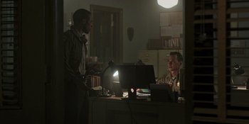 Movie still from “Teen Wolf: The Movie” (2023), directed by Russell Mulcahy – Two men sitting in front of computers in an office; Medium shot, Over the shoulder angle