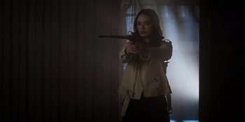 Movie still from “Teen Wolf: The Movie” (2023), directed by Russell Mulcahy – A woman is holding a gun in a room; Medium shot, Low angle
