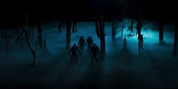 Movie still from “Teen Wolf: The Movie” (2023), directed by Russell Mulcahy – A group of people walking through a dark forest at night; Wide shot, Low angle