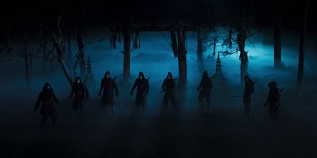 Movie still from “Teen Wolf: The Movie” (2023), directed by Russell Mulcahy – A group of people in a dark forest with fog; Wide shot, Low angle