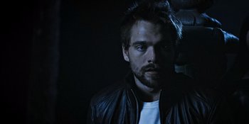Movie still from “Teen Wolf: The Movie” (2023), directed by Russell Mulcahy – A man in a leather jacket looking at the camera; Close Up shot, Low angle