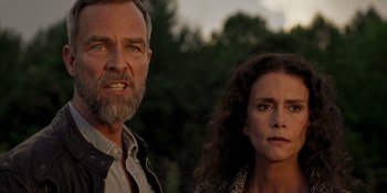 Movie still from “Teen Wolf: The Movie” (2023), directed by Russell Mulcahy – A man and a woman standing next to each other in front of trees; Close Up shot, Low angle