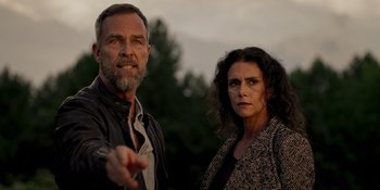 Movie still from “Teen Wolf: The Movie” (2023), directed by Russell Mulcahy – A man and a woman standing next to each other in front of trees; Close Up shot, Low angle