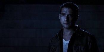 Movie still from “Teen Wolf: The Movie” (2023), directed by Russell Mulcahy – A man in a dark room with a light shining on him; Close Up shot, Over the shoulder angle