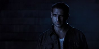 Movie still from “Teen Wolf: The Movie” (2023), directed by Russell Mulcahy – A man in a black jacket is standing in the dark; Close Up shot, High angle