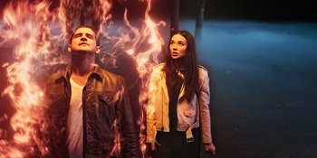 Movie still from “Teen Wolf: The Movie” (2023), directed by Russell Mulcahy – A man and a woman standing next to each other in front of fire; Medium shot, Low angle