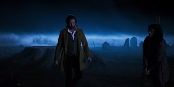 Movie still from “Teen Wolf: The Movie” (2023), directed by Russell Mulcahy – A man in a trench coat walking in the dark; Wide shot, Low angle