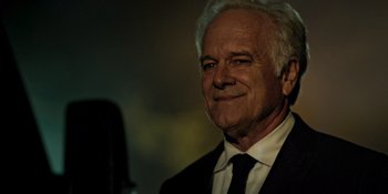 Movie still from “Teen Wolf: The Movie” (2023), directed by Russell Mulcahy – An older man wearing a suit and tie smiling; Close Up shot, Low angle