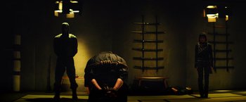 Movie still from “Teenage Mutant Ninja Turtles” (2014), directed by Jonathan Liebesman – A person is standing in front of a row of swords in a dark room; Wide shot, Over the shoulder angle