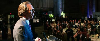 Movie still from “Teenage Mutant Ninja Turtles” (2014), directed by Jonathan Liebesman – A man standing at a podium in front of an audience; Medium shot, Over the shoulder angle