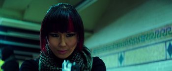 Movie still from “Teenage Mutant Ninja Turtles” (2014), directed by Jonathan Liebesman – A woman with red and black hair is holding a gun in her hand; Close Up shot, High angle