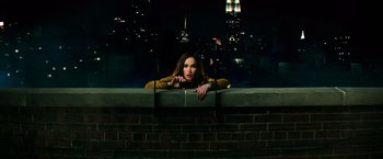 Movie still from “Teenage Mutant Ninja Turtles” (2014), directed by Jonathan Liebesman – A woman leaning up against a wall in a city at night; Medium shot, High angle