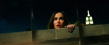 Movie still from “Teenage Mutant Ninja Turtles” (2014), directed by Jonathan Liebesman – A woman leaning on a wall looking over a ledge; Close Up shot, Low angle