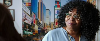 Movie still from “Teenage Mutant Ninja Turtles” (2014), directed by Jonathan Liebesman – A person wearing glasses near a city; Close Up shot, Over the shoulder angle