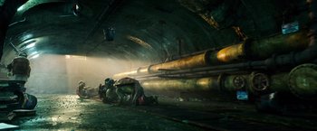 Movie still from “Teenage Mutant Ninja Turtles” (2014), directed by Jonathan Liebesman – A group of people are sitting on the ground in a tunnel; Extreme Wide shot, Low angle