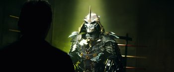 Movie still from “Teenage Mutant Ninja Turtles” (2014), directed by Jonathan Liebesman – A man dressed as a knight in a metal suit; Medium shot, Over the shoulder angle