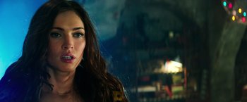 Movie still from “Teenage Mutant Ninja Turtles” (2014), directed by Jonathan Liebesman – A beautiful woman with long brown hair standing in front of a building; Close Up shot, Over the shoulder angle