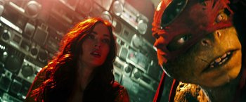 Movie still from “Teenage Mutant Ninja Turtles” (2014), directed by Jonathan Liebesman – A man and a woman are standing next to each other; Close Up shot, Over the shoulder angle