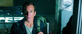 Movie still from “Teenage Mutant Ninja Turtles” (2014), directed by Jonathan Liebesman – A man with a backpack sitting in a room; Close Up shot, Low angle