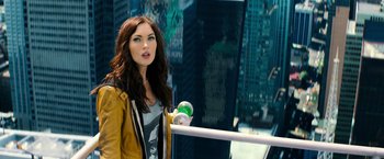 Movie still from “Teenage Mutant Ninja Turtles” (2014), directed by Jonathan Liebesman – A beautiful young woman holding a skateboard while standing next to a building; Close Up shot, Overhead angle