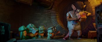 Movie still from “Teenage Mutant Ninja Turtles: Mutant Mayhem” (2023), directed by Jeff Rowe – A group of small figurines sitting next to each other; Wide shot, Low angle