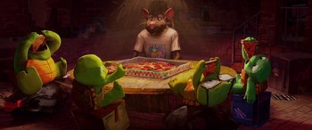 Movie still from “Teenage Mutant Ninja Turtles: Mutant Mayhem” (2023), directed by Jeff Rowe – A group of people sitting at a table with pizza; Medium shot, Over the shoulder angle