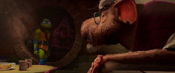 Movie still from “Teenage Mutant Ninja Turtles: Mutant Mayhem” (2023), directed by Jeff Rowe – A rat with glasses and a brick wall in the background; Medium shot, Over the shoulder angle