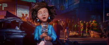 Movie still from “Teenage Mutant Ninja Turtles: Mutant Mayhem” (2023), directed by Jeff Rowe – An illustration of an african american woman holding a microphone in front of a crowd of onlookers; Medium shot, Low angle
