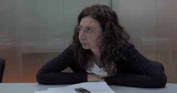 Movie still from “Collective” (2019), directed by Alexander Nanau – A woman sitting at a table with a cell phone in front of her; Close Up shot, High angle