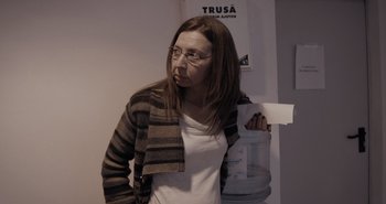 Movie still from “Collective” (2019), directed by Alexander Nanau – A woman holding a piece of paper in front of her face; Medium shot, Low angle
