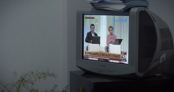 Movie still from “Collective” (2019), directed by Alexander Nanau – A television screen with two people sitting on it; Extreme Close Up shot, High angle