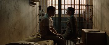 Movie still from “Terminator Salvation” (2009), directed by McG – A man and a woman sitting on a bed in front of a jail cell; Medium shot, High angle