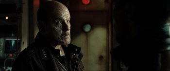 Movie still from “Terminator Salvation” (2009), directed by McG – A man with a shaved head and a goatee looking into the distance; Close Up shot, Over the shoulder angle