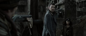 Movie still from “Terminator Salvation” (2009), directed by McG – A man standing next to a wall holding a gun in his hand; Close Up shot, Over the shoulder angle