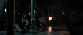 Movie still from “Terminator Salvation” (2009), directed by McG – A group of people sitting on a bench in a dark room; Wide shot, Over the shoulder angle