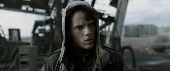 Movie still from “Terminator Salvation” (2009), directed by McG – A young man wearing a hooded jacket in the woods; Close Up shot, Over the shoulder angle