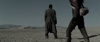 Movie still from “Terminator Salvation” (2009), directed by McG – A man in a trench coat standing in the desert; Wide shot, Low angle