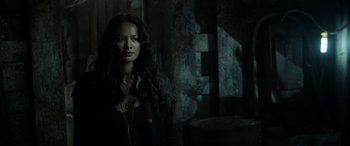 Movie still from “Terminator Salvation” (2009), directed by McG – A woman standing in a dark room wearing a necklace; Close Up shot, Over the shoulder angle