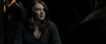 Movie still from “Terminator Salvation” (2009), directed by McG – A woman with long red hair is sitting in a dimly - lit room; Close Up shot, Low angle